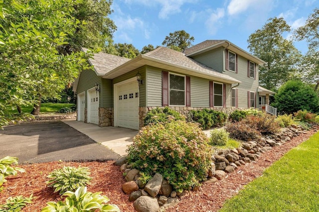 view of front of property featuring an attached garage, stone siding, driveway, and roof with shingles