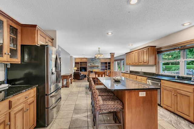 kitchen featuring a kitchen island, a breakfast bar, stainless steel appliances, a sink, and glass insert cabinets