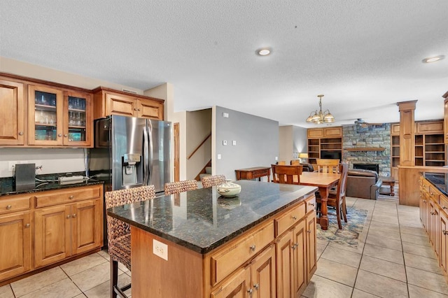 kitchen featuring a center island, glass insert cabinets, stainless steel fridge with ice dispenser, light tile patterned flooring, and a textured ceiling