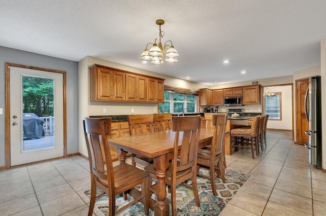 dining space with light tile patterned floors, a textured ceiling, and baseboards