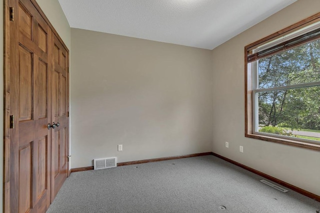 carpeted spare room featuring baseboards and visible vents