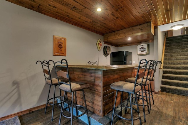 bar featuring a bar, wooden ceiling, stairs, and freestanding refrigerator