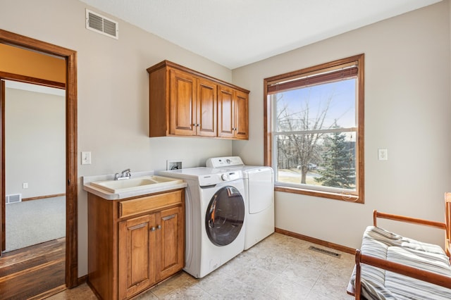 laundry room featuring washer and clothes dryer, visible vents, cabinet space, and a sink