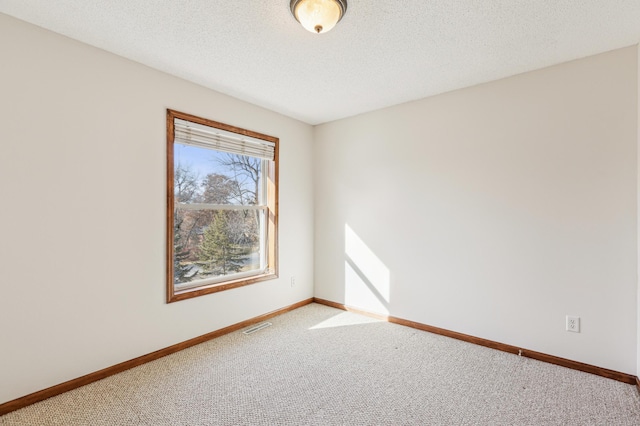 carpeted spare room featuring baseboards, visible vents, and a textured ceiling