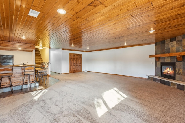 carpeted living area with wooden ceiling, a fireplace, crown molding, baseboards, and a dry bar