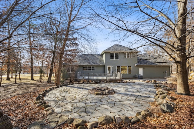 view of front of home with a patio, a wooden deck, central AC, and roof with shingles