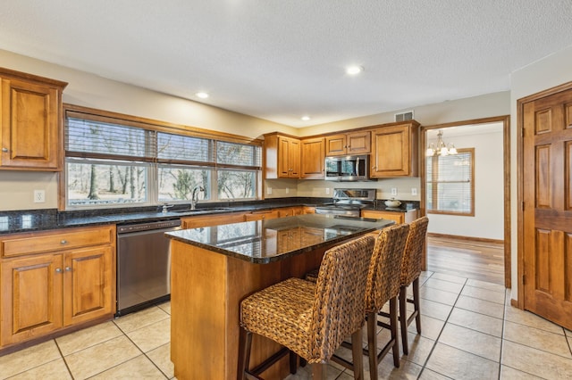 kitchen featuring visible vents, brown cabinets, a sink, appliances with stainless steel finishes, and a breakfast bar area