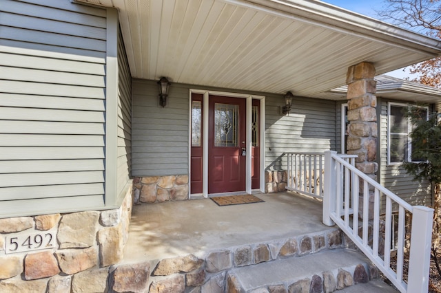 view of exterior entry featuring covered porch and stone siding