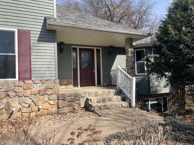 property entrance with roof with shingles and a porch