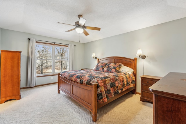 bedroom with baseboards, light carpet, a textured ceiling, and a ceiling fan