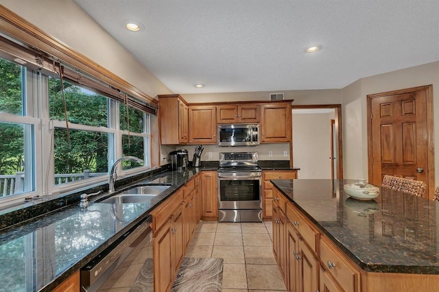 5492 Garden Hills Dr, Saint Augusta, MN 56301 - kitchen featuring a sink, stainless steel appliances, dark stone counters, light tile patterned flooring, and brown cabinetry