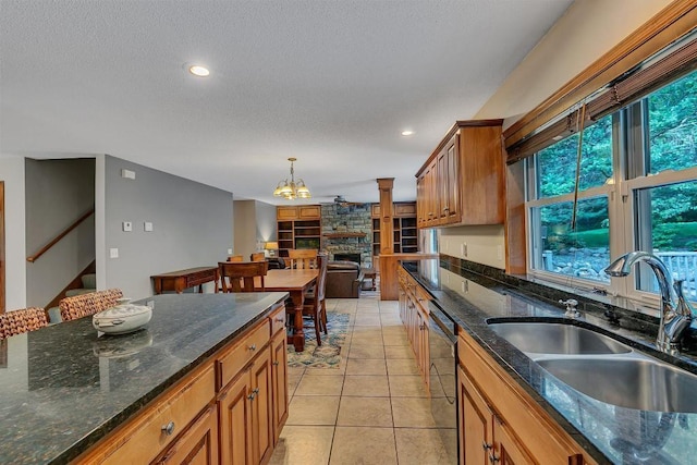 5492 Garden Hills Dr, Saint Augusta, MN 56301 - kitchen with light tile patterned floors, brown cabinetry, a fireplace, a sink, and dishwasher