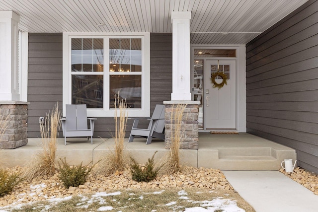 view of exterior entry featuring covered porch and stone siding