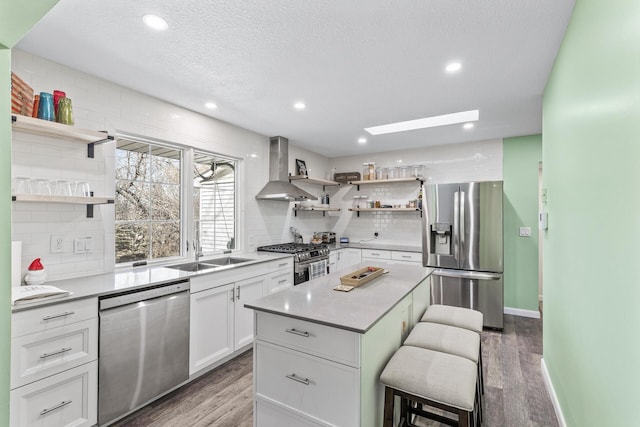 kitchen with open shelves, a kitchen breakfast bar, appliances with stainless steel finishes, and wall chimney exhaust hood