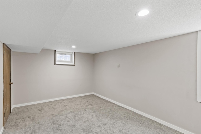 basement featuring recessed lighting, a textured ceiling, baseboards, and carpet