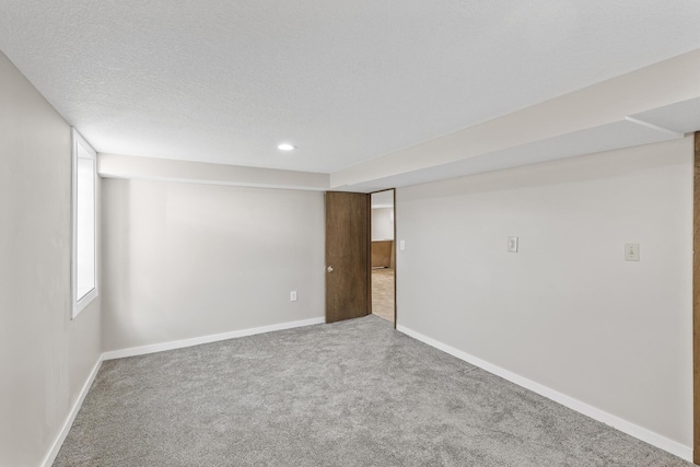 carpeted spare room with a textured ceiling and baseboards