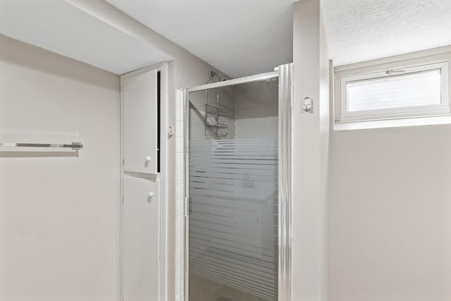 full bathroom featuring a textured ceiling and a stall shower