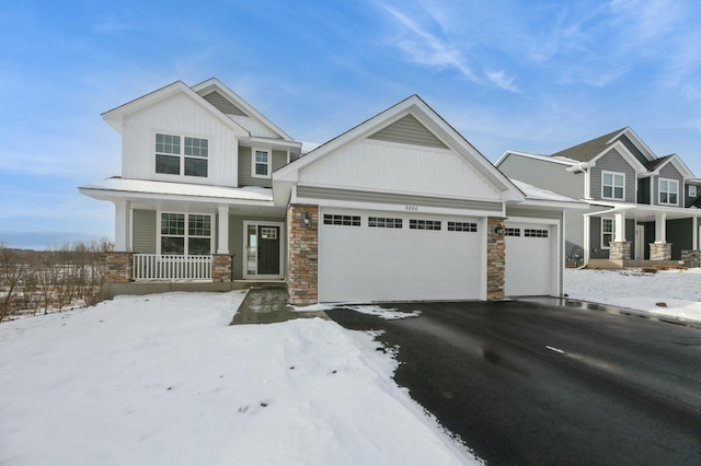 craftsman house featuring driveway, stone siding, board and batten siding, covered porch, and a garage