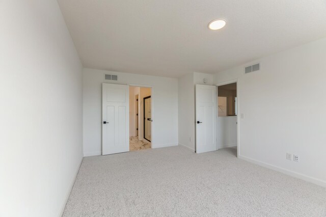 unfurnished bedroom with visible vents, baseboards, and light colored carpet