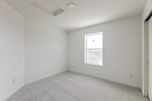 spare room with light carpet, visible vents, and baseboards