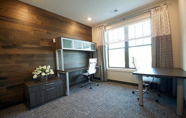 office space featuring visible vents, baseboards, wood walls, and carpet flooring