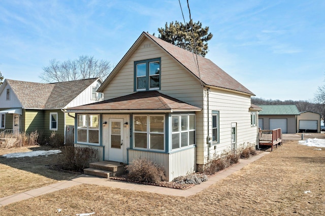 bungalow-style home featuring an outbuilding and roof with shingles