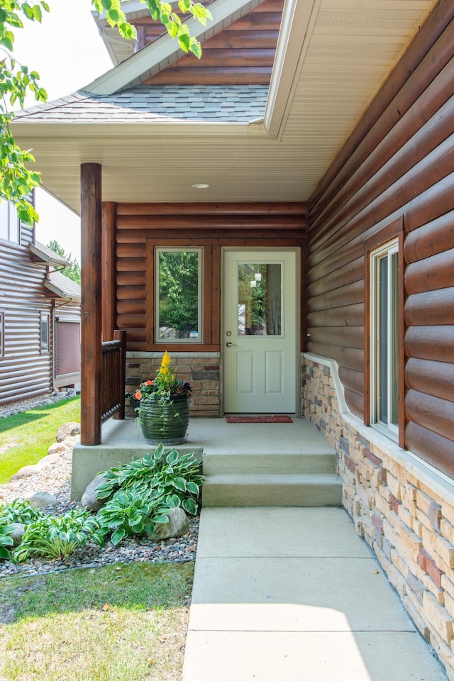 entrance to property with stone siding, a porch, and a shingled roof