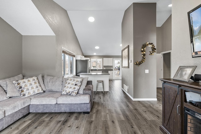 living room with recessed lighting, wood finished floors, and vaulted ceiling