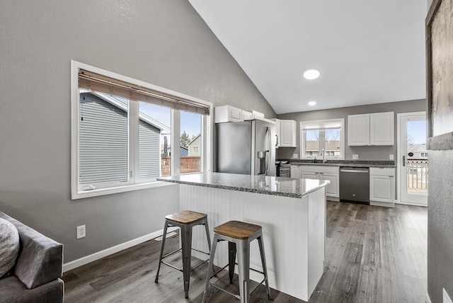 kitchen featuring stainless steel appliances, a kitchen breakfast bar, baseboards, and wood finished floors