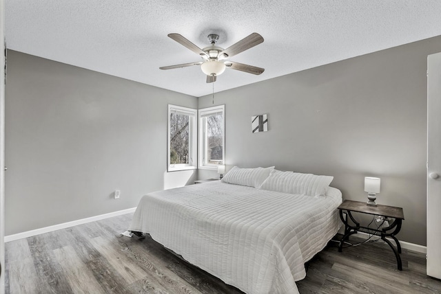 bedroom featuring ceiling fan, baseboards, a textured ceiling, and wood finished floors