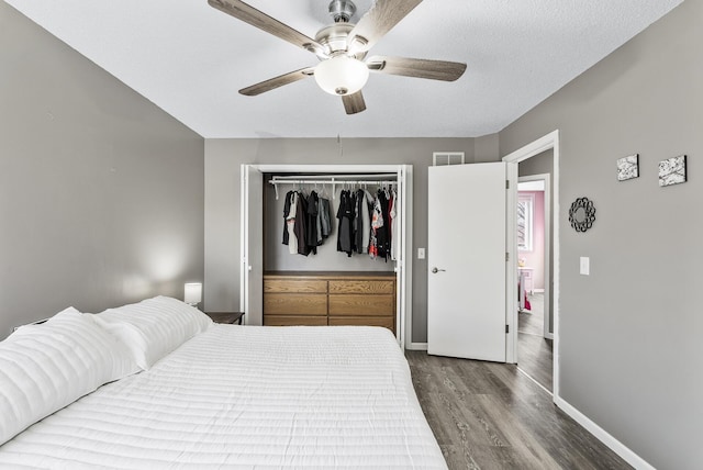 bedroom with visible vents, ceiling fan, baseboards, wood finished floors, and a closet