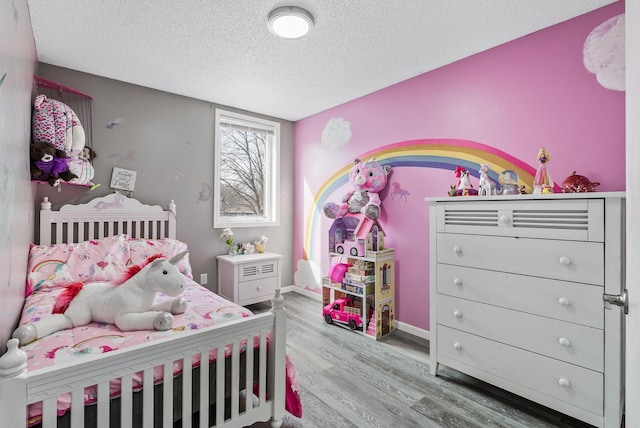 bedroom with a textured ceiling, baseboards, and wood finished floors