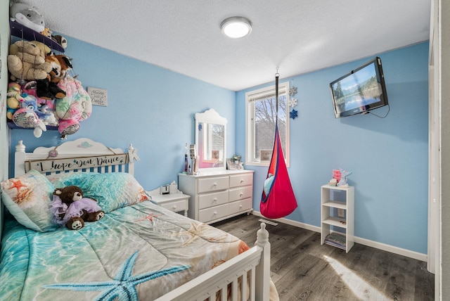 bedroom featuring wood finished floors, baseboards, and a textured ceiling