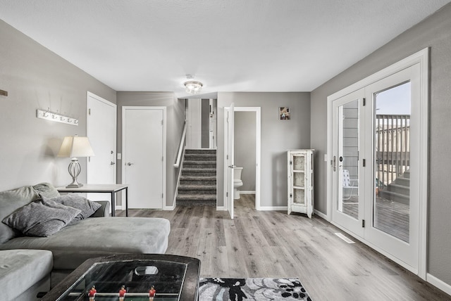 living room with stairway, baseboards, wood finished floors, and french doors