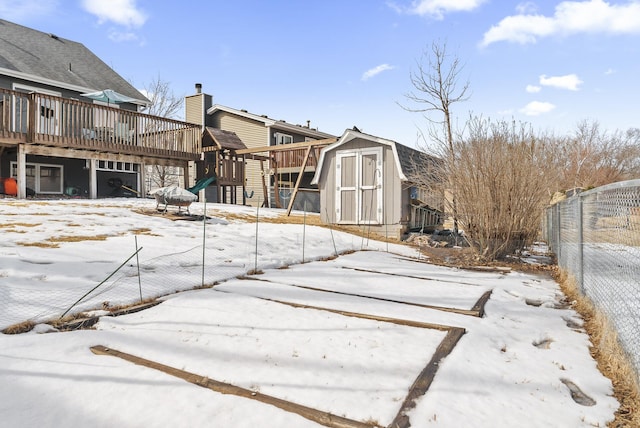 snow covered back of property featuring an outbuilding, fence, a shed, a gambrel roof, and a chimney