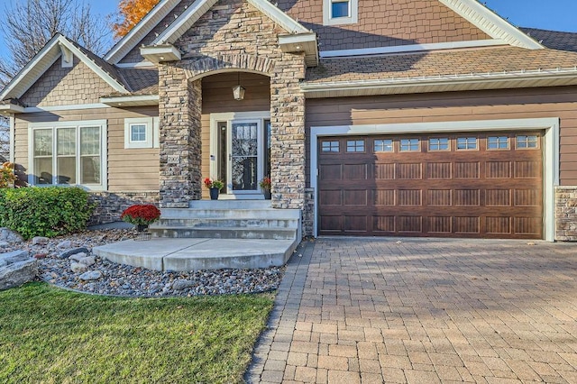 craftsman-style house with stone siding, a garage, decorative driveway, and roof with shingles