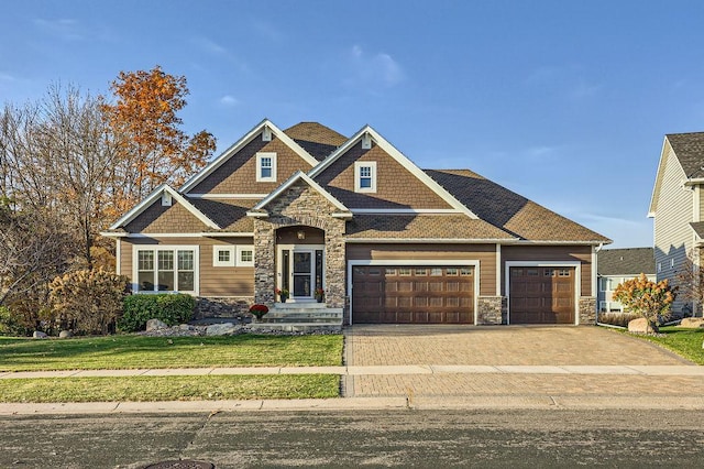 craftsman house featuring stone siding, driveway, a front yard, and a garage