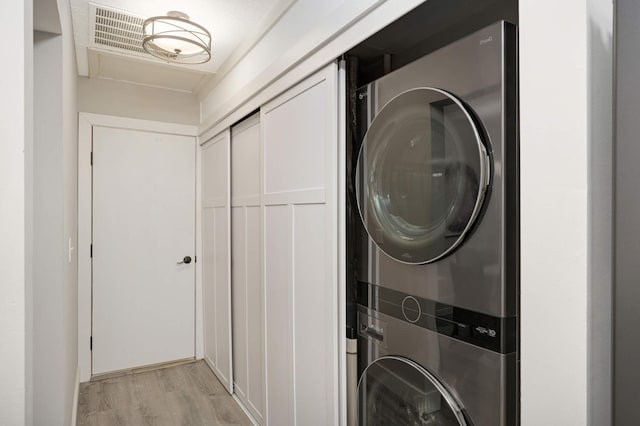 laundry room with light wood finished floors, laundry area, and stacked washing maching and dryer