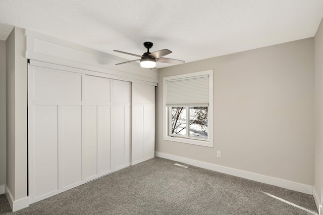 unfurnished bedroom with visible vents, a textured ceiling, a closet, carpet, and baseboards