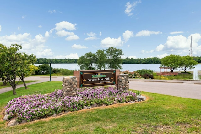 community sign with a lawn and a water view
