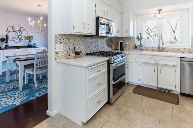 kitchen featuring backsplash, appliances with stainless steel finishes, white cabinetry, and light countertops