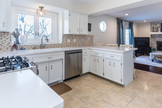 kitchen featuring a peninsula, a sink, light countertops, stainless steel dishwasher, and open floor plan