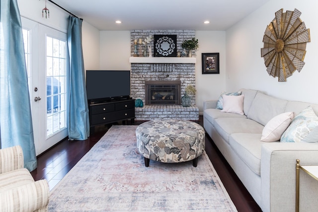 living area featuring a brick fireplace, recessed lighting, dark wood-style flooring, and french doors