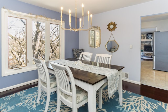 dining room with visible vents, wood finished floors, baseboards, and a chandelier