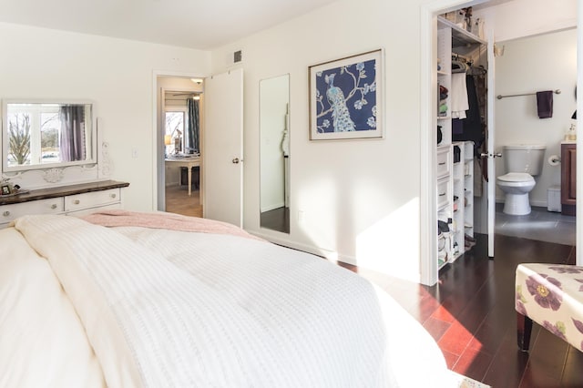 bedroom with visible vents, ensuite bathroom, wood finished floors, a closet, and a spacious closet