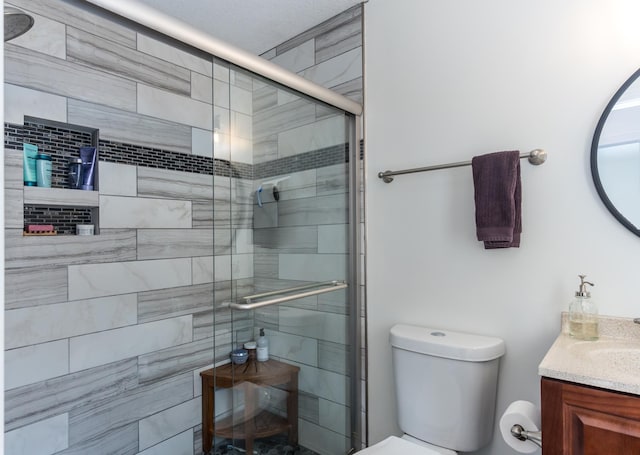 bathroom with vanity, a shower stall, and toilet