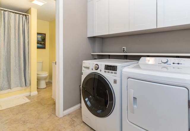 washroom featuring cabinet space, baseboards, and washer and clothes dryer