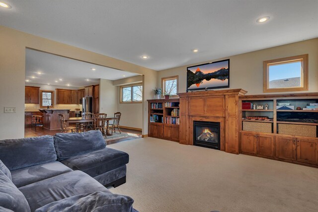 carpeted living room featuring a glass covered fireplace and recessed lighting