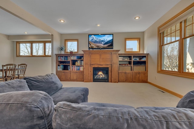 living room featuring carpet, visible vents, baseboards, recessed lighting, and a glass covered fireplace