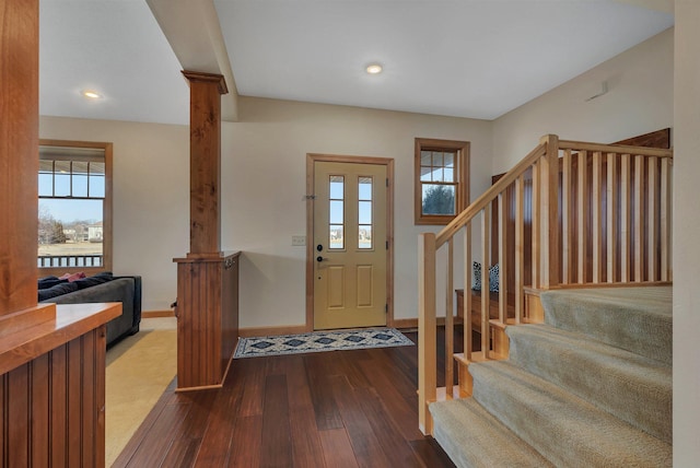 foyer with stairs, dark wood-style floors, decorative columns, and a healthy amount of sunlight